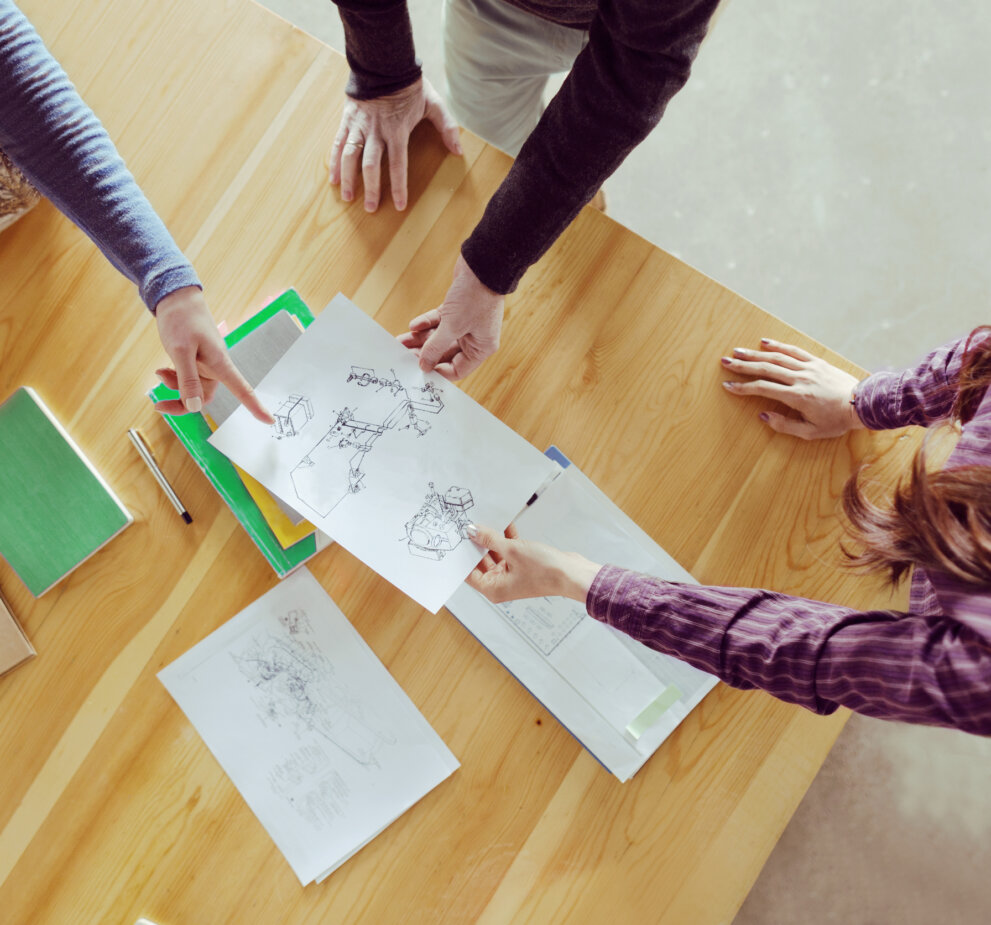 Professionals review a schematic around a table.