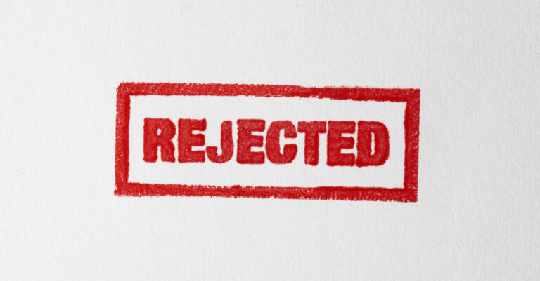 Rejected red grunge stamp on white paper.