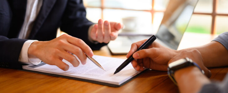 Closeup lawyer or insurance agent pointing at contract showing male client where to signature sign.