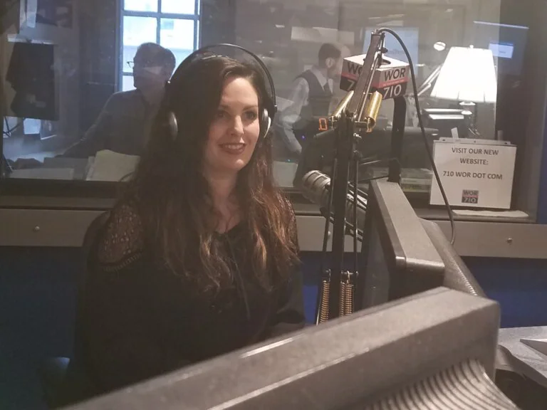 `Woman wearing headphones speaking into microphone in WOR 710 radio studio`