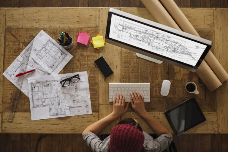 Architect working on blueprints and computer aided design (CAD)