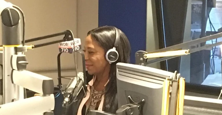 Woman in a radio studio wearing headphones, speaking into a WOR 710 microphone.