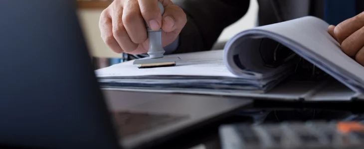 person stamping a book with a laptop trademarks