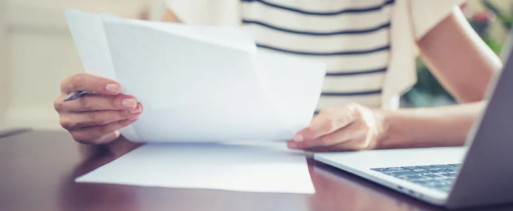 person holding paper with laptop on desk patents