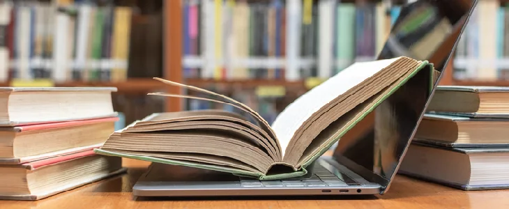 Laptop open with a textbook on a table